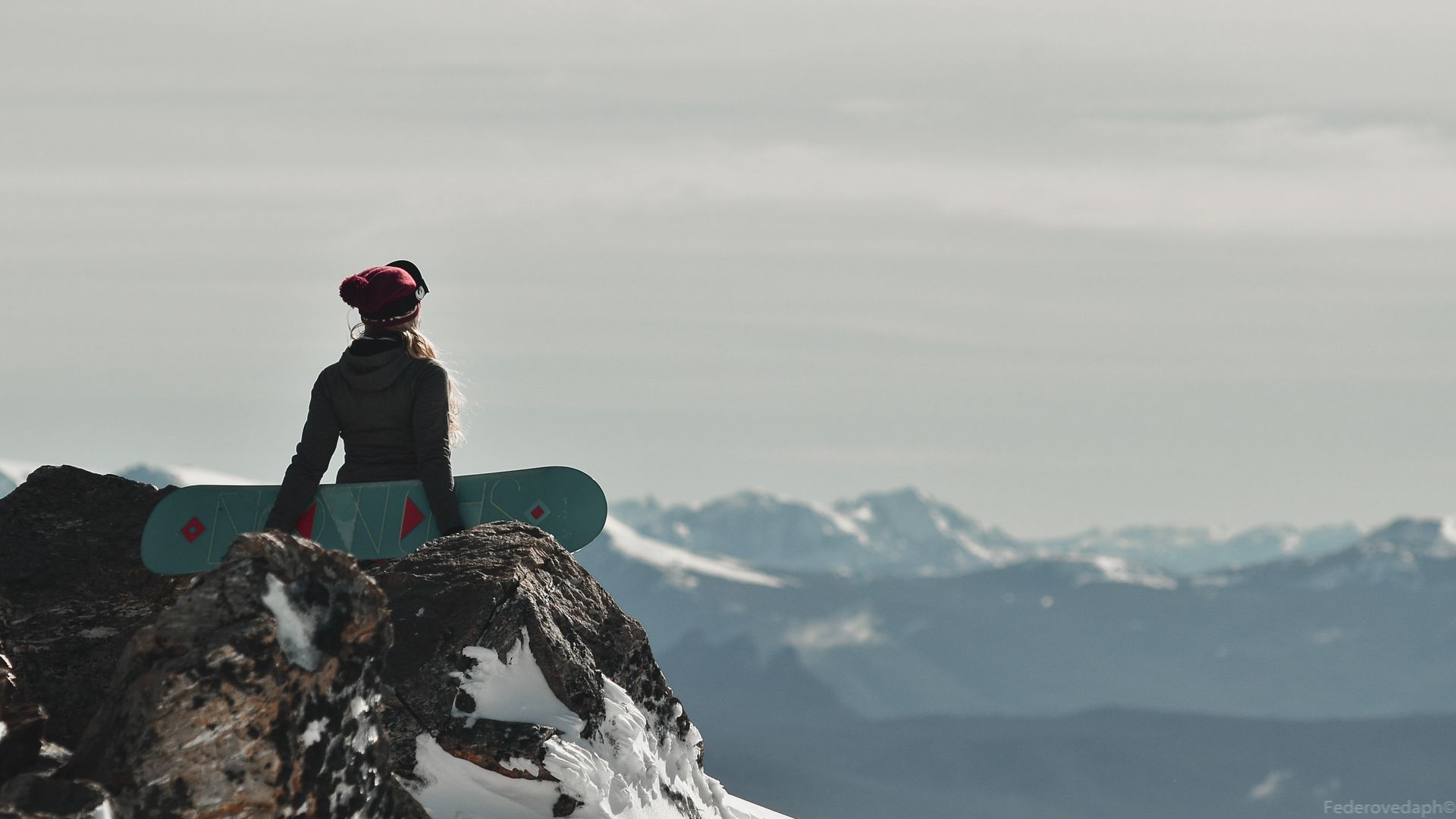 A snowboarder catching air against a blue alpine sky